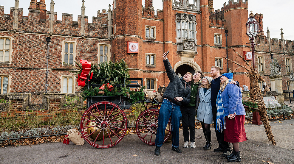 A group of friends taking a selfie in front of Christmas decorations at Hampton Court Palace's Festive Fayre